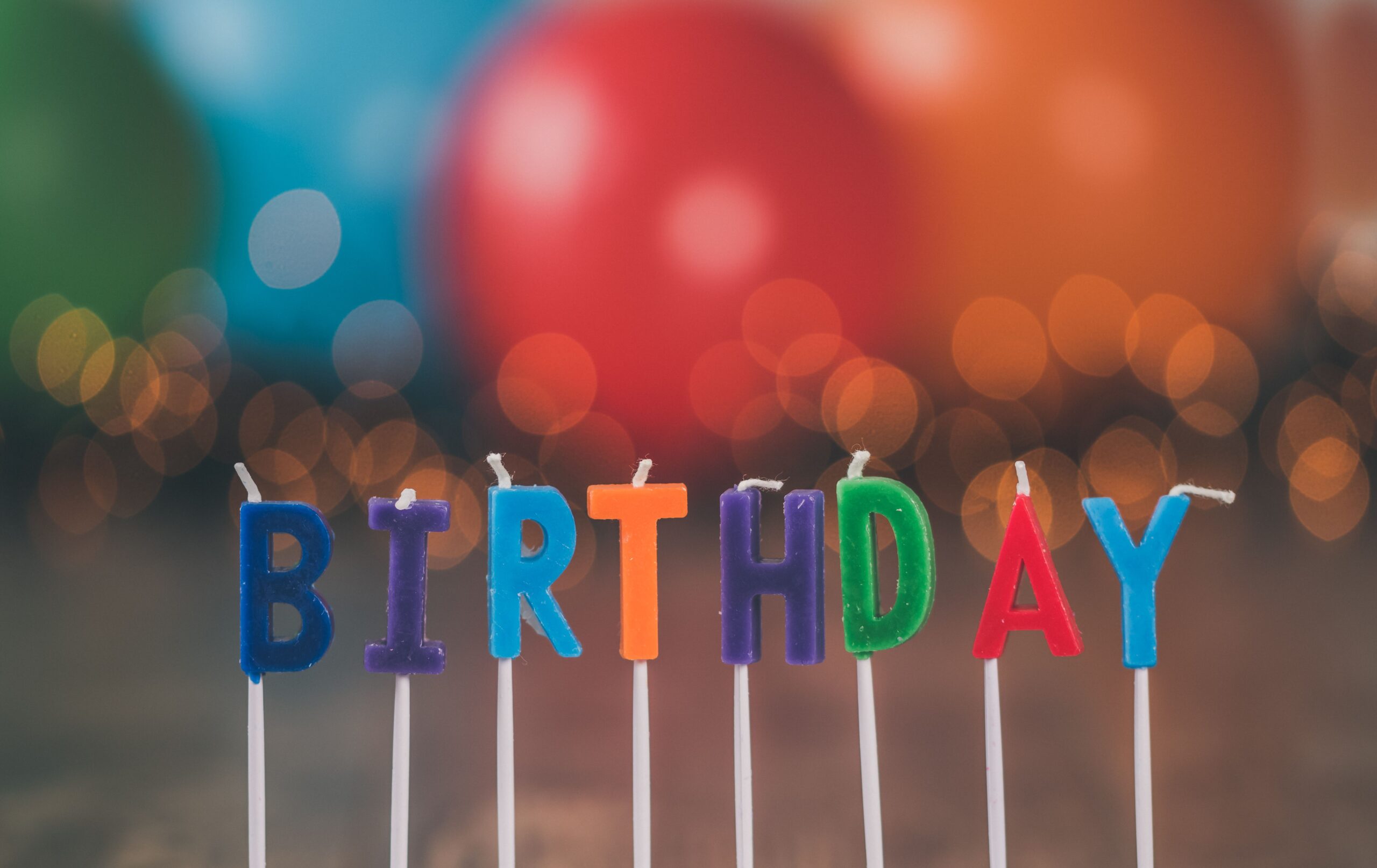 Vibrant birthday candles spelling "BIRTHDAY" against a festive, blurred background.